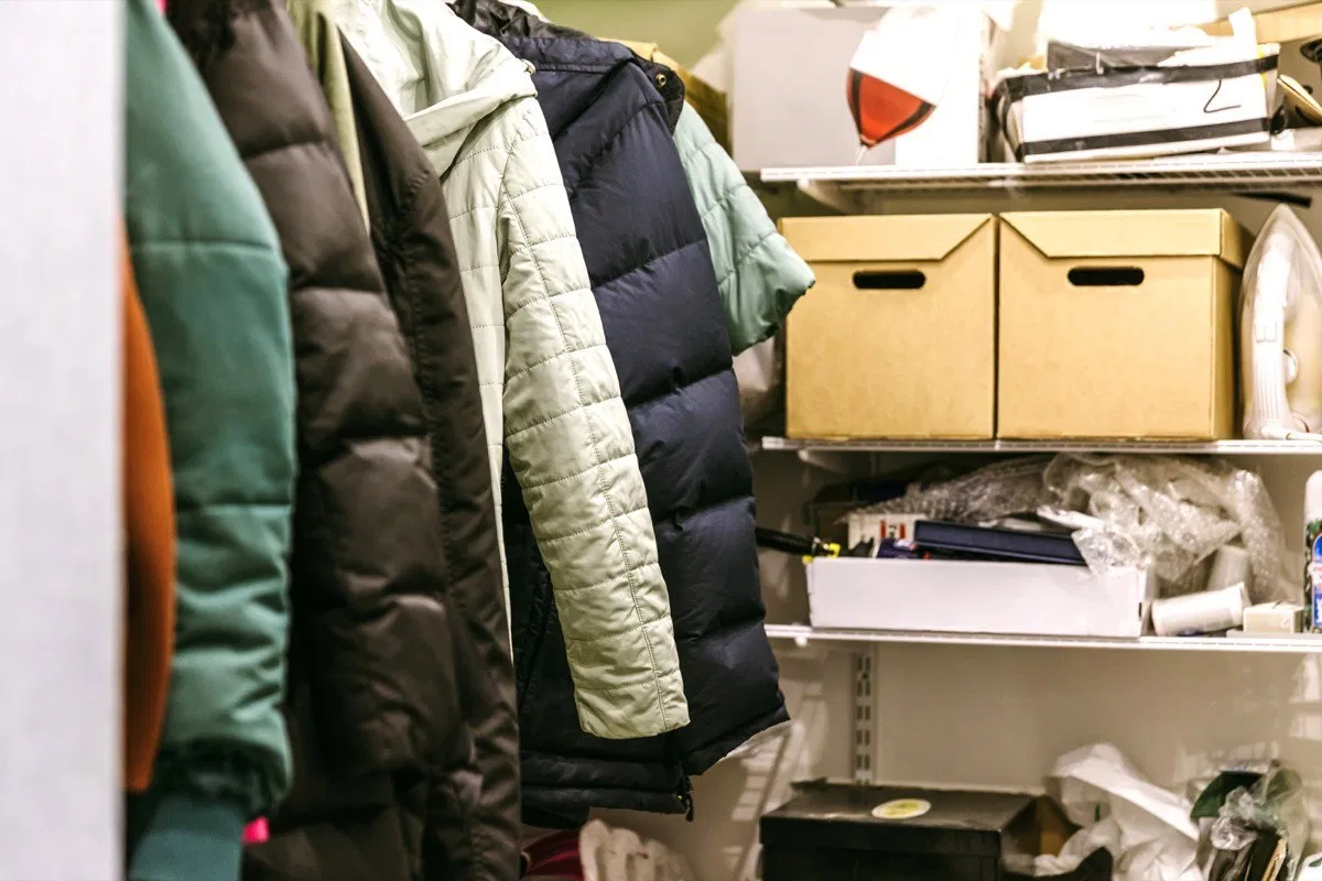 A cluttered closet with boxes and clothes